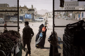 Una delle foto del reportage in Yemen con cui Lorenzo Tugnoli ha vinto il Pulitzer e il World Press Photo. Una donna con il velo chiede l'elemosina fuori da un negozio di frutta (credit Washington Post/Contrasto)