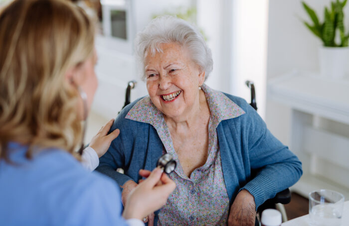 Nurse Examining Senior Patient With Stethoscope At Her Home.