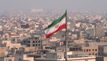 The City Of Tehran With The Waving Iranian Flag In The Foreground